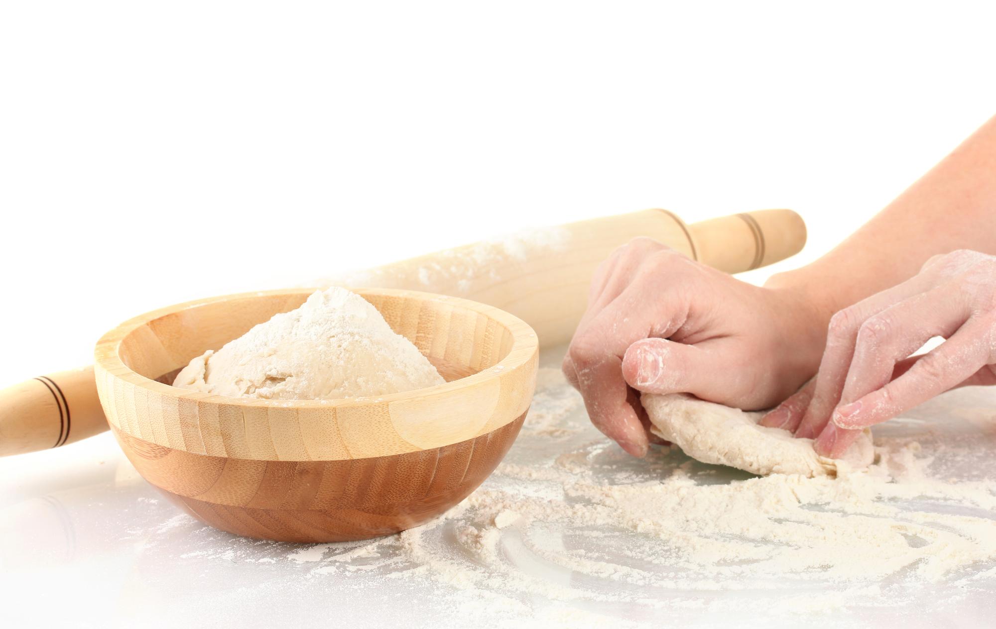 hands shaping dough on wooden board